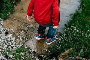 Young child in trainers on wet path wearing a red top